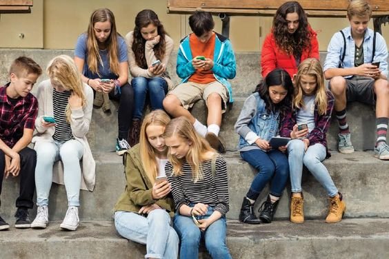 Several youths sitting on stairs, absorbed in using their smartpho