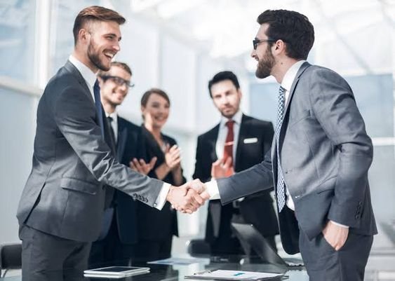 Two professionals shaking hands in an office, symbolizing a successful business deal.